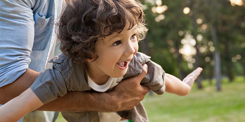 Child being lifted joyfully into the air by a caregiver