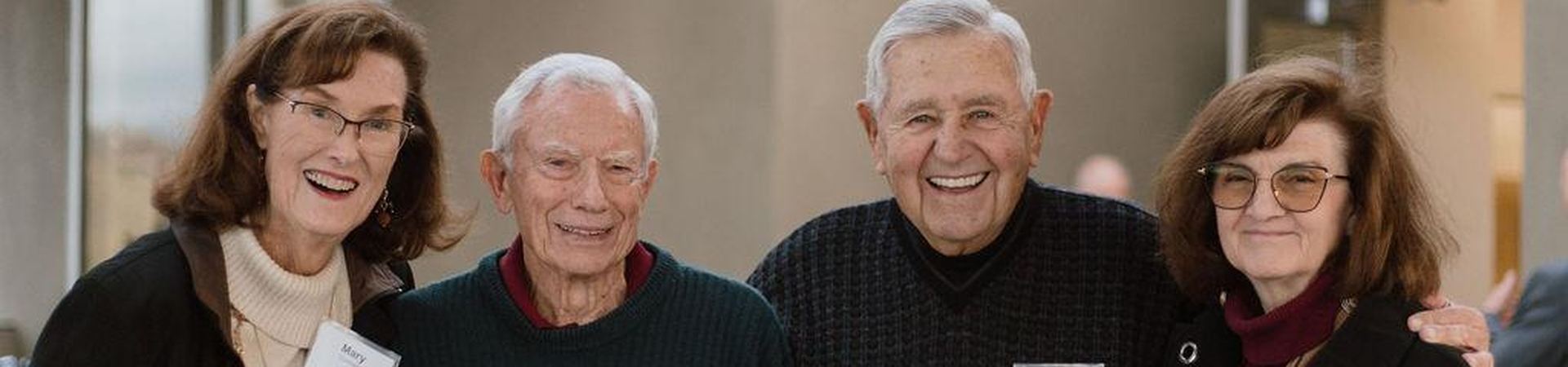 Four smiling retirees with their arms around one another at a Foundation gathering